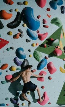 Man bouldering indoors on a colorful climbing wall, showcasing strength and agility.